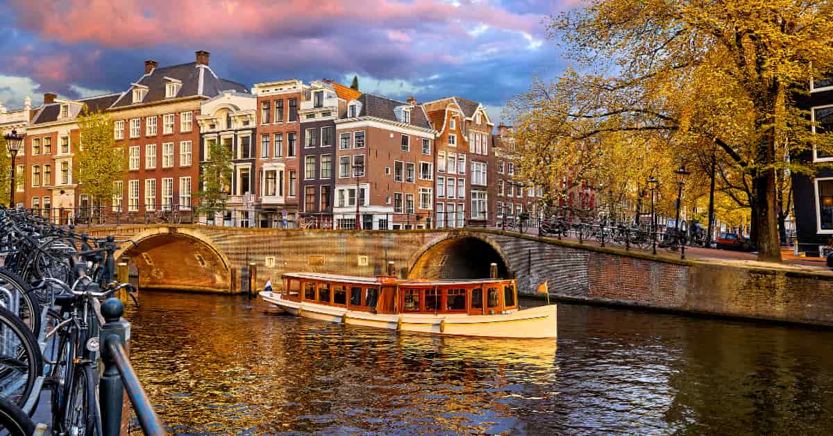 Canal view with a boat in Amsterdam at sunset.