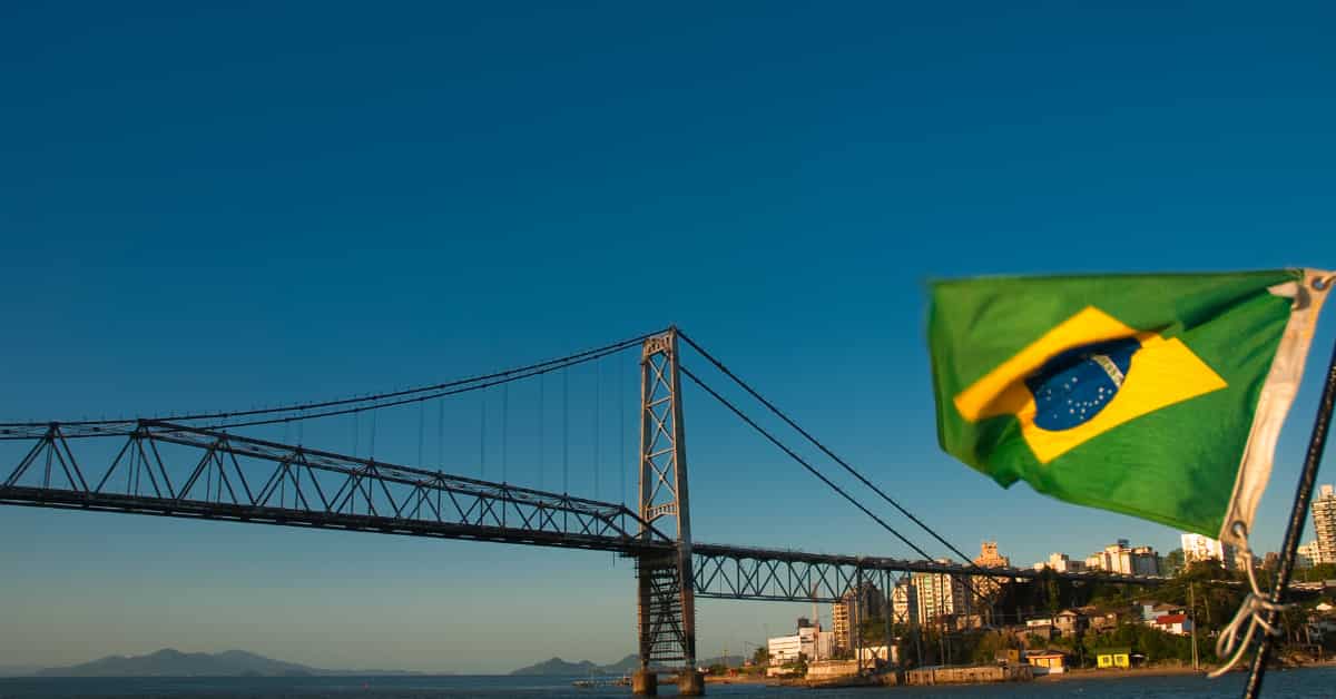 brazil flag near bridge and coastline at sunset.