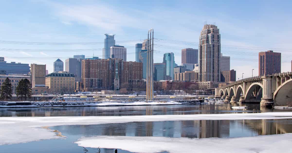 minneapolis skyline in winter with river and bridge.