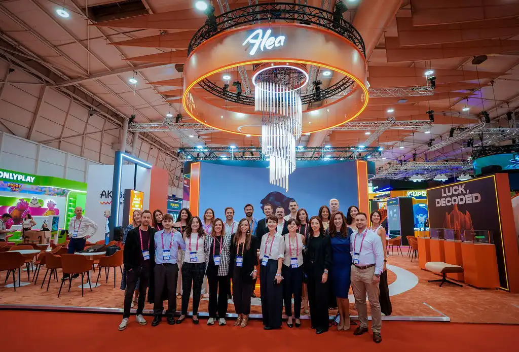 The Alea team poses at its booth beneath an illuminated logo at SBC Summit Lisbon 2026.