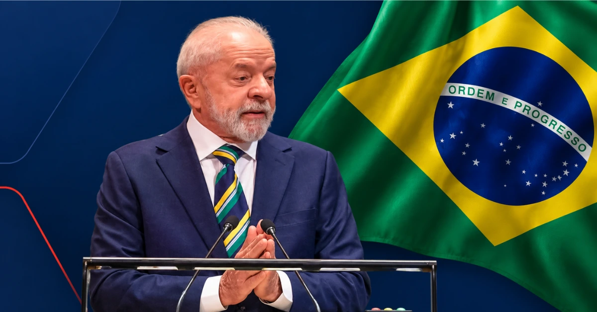 Luiz Inácio Lula da Silva pictured in front of the Brazilian flag against a dark blue background.