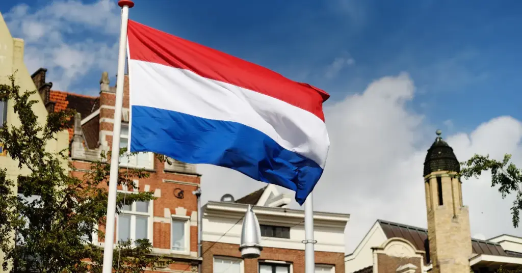 Dutch flag flying above historic buildings under a blue sky in the Netherlands