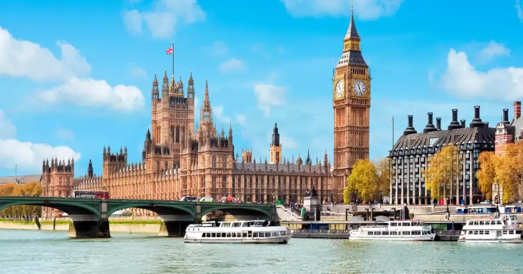 The Palace of Westminster and Elizabeth Tower beside the River Thames in London, with Westminster Bridge and boats in the foreground.