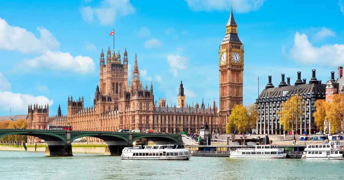 The Palace of Westminster and Elizabeth Tower beside the River Thames in London, with Westminster Bridge and boats in the foreground.
